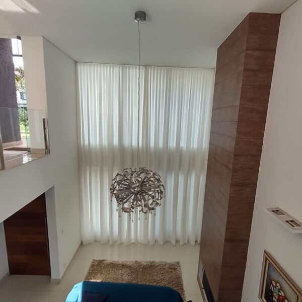 Cortina translúcida em sala com pé-direito duplo: a automação permite controlar a entrada de luz com um comando.