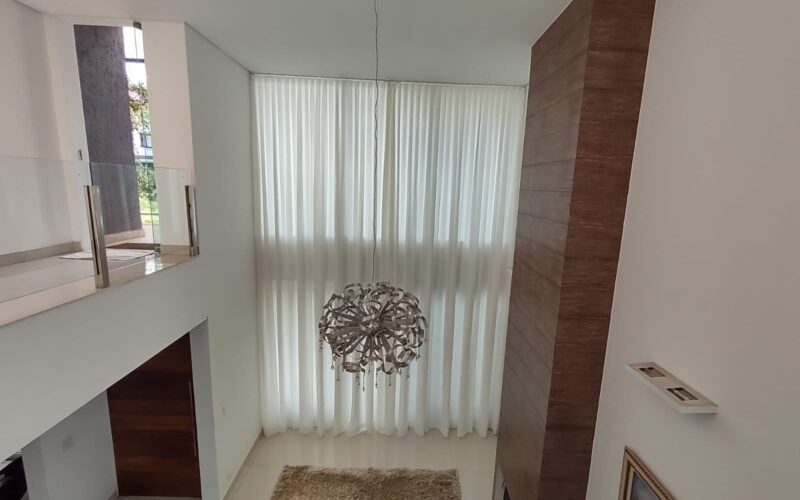 Cortina translúcida em sala com pé-direito duplo: a automação permite controlar a entrada de luz com um comando.